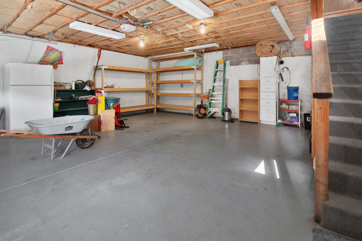 Oversized residential garage with bare concrete floor, shelving and hobby storage before coating